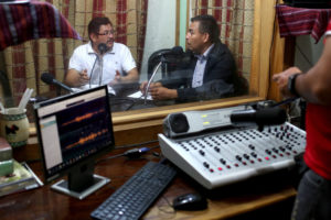 A Justice in Motion defender named Palacios, right, appears on a radio show hosted by Everado Cuyuch Lopez to talk about family separation.