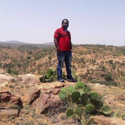 A man stands in a desert environment posing for a photo