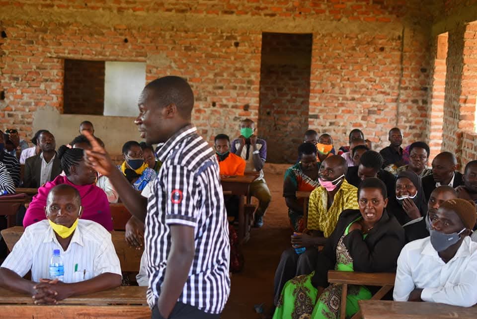 A man addresses a classroom of adults in a brick room.