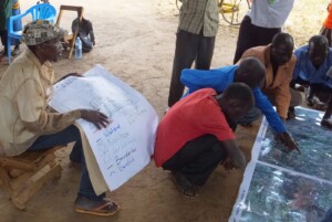 An elder monitors the mapping to ensure it follows the legend agreed upon during the first sketch map