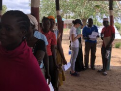 Community members on a queue during mobile birth registration while Haki Center Paralegals and Learning exchange participants have discussions